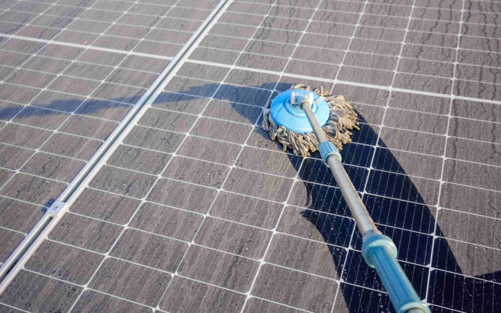 Close-up of solar panel cleaning using a rotating brush tool on a rooftop.