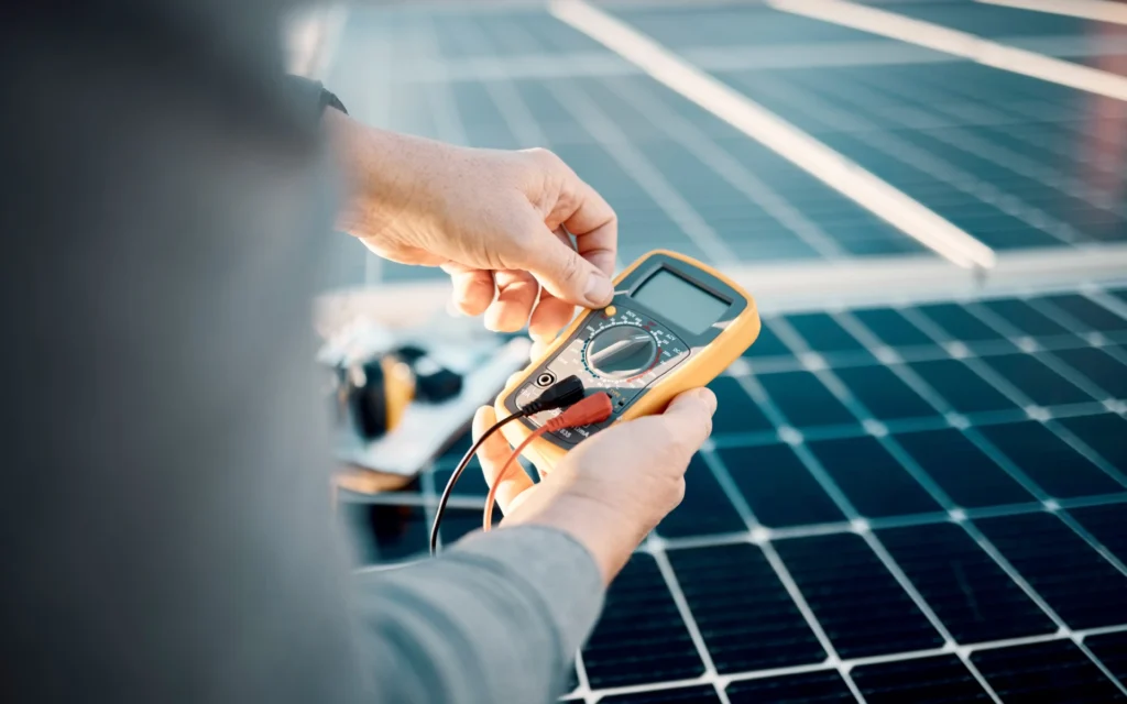 A technician uses a multimeter for solar panel electrical repair on a rooftop installation.
