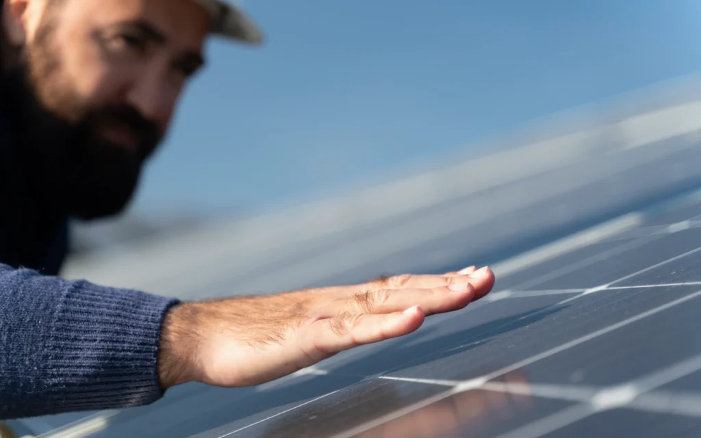 A technician gently runs his hand across a solar panel while inspecting it as part of routine solar maintenance.