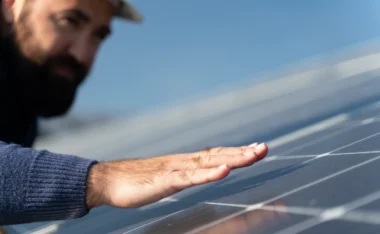 A technician gently runs his hand across a solar panel while inspecting it as part of routine solar maintenance.