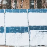 Snow-covered solar panels in winter illustrate changes in solar panel performance by season as reduced sunlight and weather conditions affect energy output.