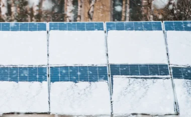 Snow-covered solar panels in winter illustrate changes in solar panel performance by season as reduced sunlight and weather conditions affect energy output.