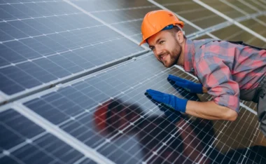 Technician in a hard hat inspecting solar panels on a rooftop, illustrating coastal weather impact on solar panels.